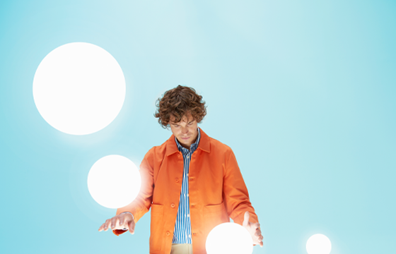 The cover of Weichert's Designing Mobility for Success Research: Part 1 shows a you man in an orange jacket and blue striped dress shirt standing at a white table holding a white orb in his left hand while three other orbs float around him.