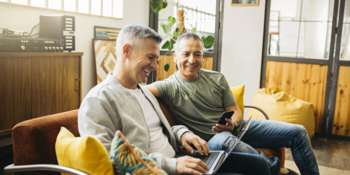 Gay couple on couch going over their home finances