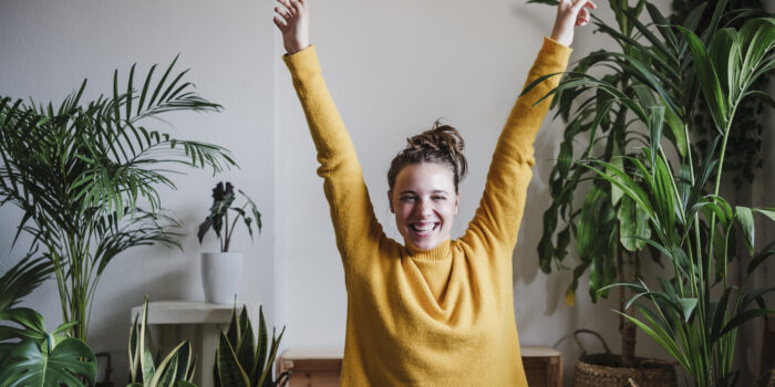 Carefree woman with hand raised sitting at home