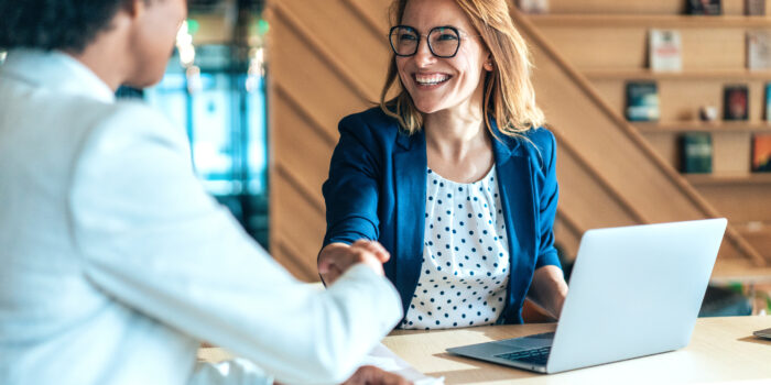Business people shaking hands in the office. Group of business persons in business meeting. Two entrepreneurs on meeting in board room. Corporate business team on meeting in modern office. Female manager discussing new project with her colleagues. Company owner on a meeting with her employee in her office.