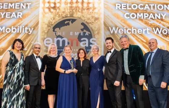 Group shown on stage holding a trophy at the EMEA emmas