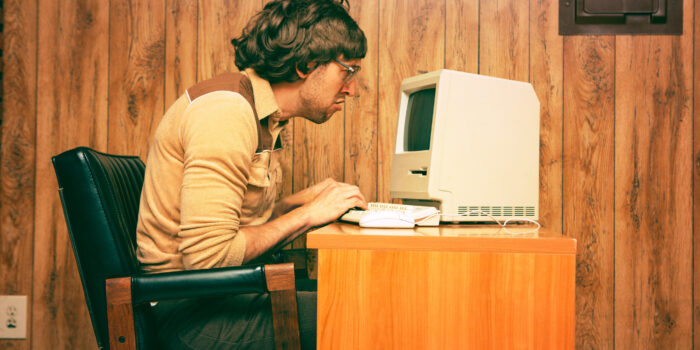 Goofy 1980s Computer Worker looking intently at a vintage computer screen