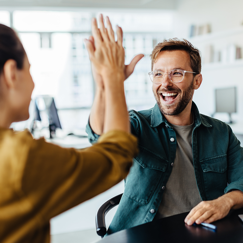 Two happy people high fiving in an office setting
