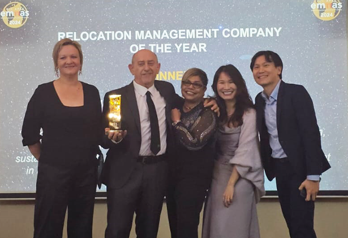 Several people posing for a picture at the RMC of the year presentation with one of them holding a trophy